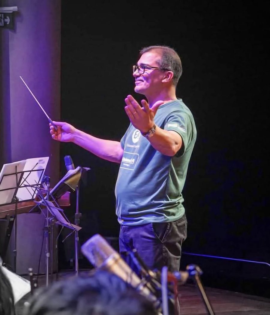 Luiz André da Silva, diretor e fundador da EArte, regendo no auditório da escola